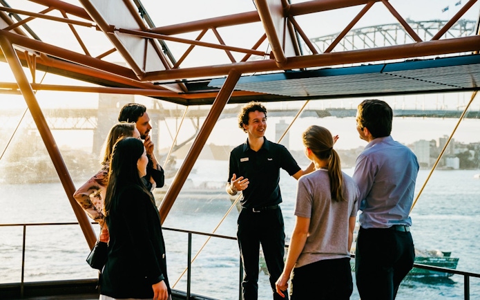 Group on a guided tour inside Sydney Opera House with Sydney Harbour Bridge view.