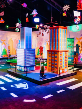 Colorful cityscape model at SuperThings: The Exhibition with hanging cartoon figures.