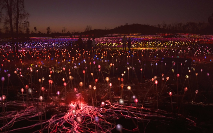 Uluru Field of Light installation at sunrise with colorful illuminated spheres.