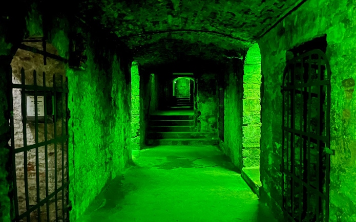 Underground passageway with green lighting on the Terror Tour in Edinburgh.