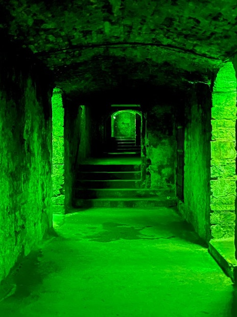 Underground passageway with green lighting on the Terror Tour in Edinburgh.