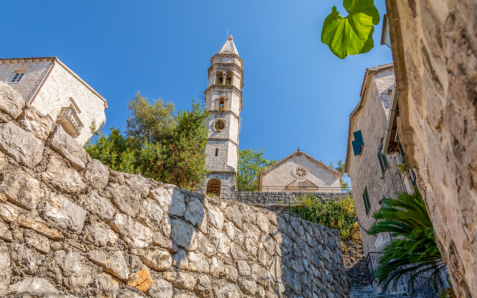 Zmajević Palace Perast stone tower and walls under clear blue sky.