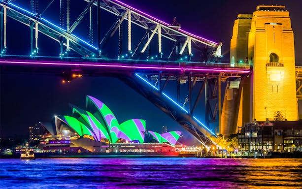 Sydney Harbour Bridge and Opera House illuminated during Vivid Sydney cruise.
