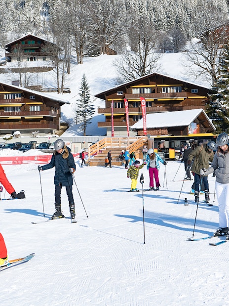Beginner skiers learning on snowy slopes in Grindelwald with wooden chalets in the background.