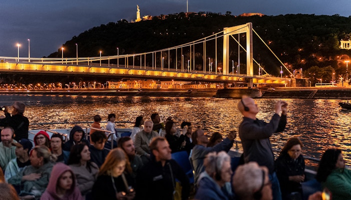 Budapest river cruise with drinks, showcasing Parliament building illuminated at night.