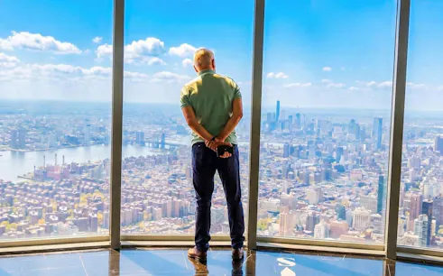 Man viewing New York City skyline from Empire State Building observatory.