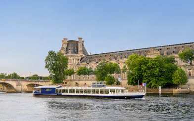 Dinner cruise boat on the Seine River passing by the Louvre Museum in Paris.