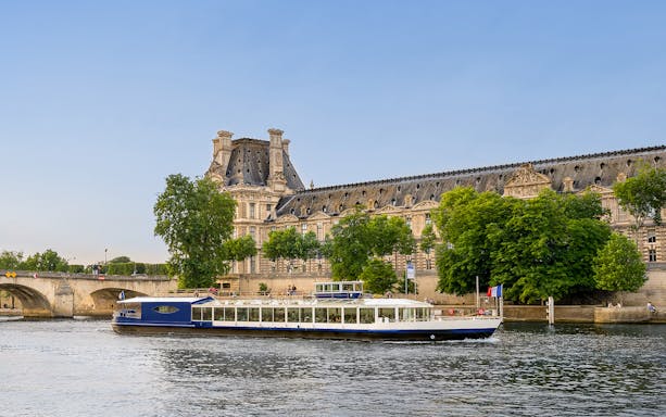 Dinner cruise boat on the Seine River passing by the Louvre Museum in Paris.