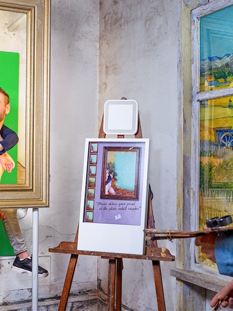 Man and child posing in frame with Vincent van Gogh figure at Madame Tussauds Amsterdam.