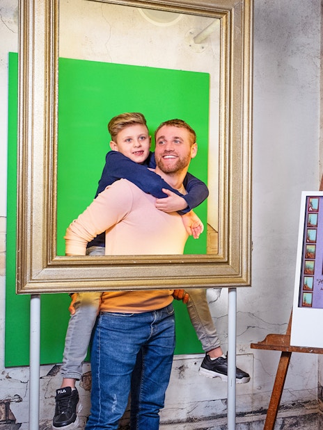 Man and child posing in frame with Vincent van Gogh figure at Madame Tussauds Amsterdam.