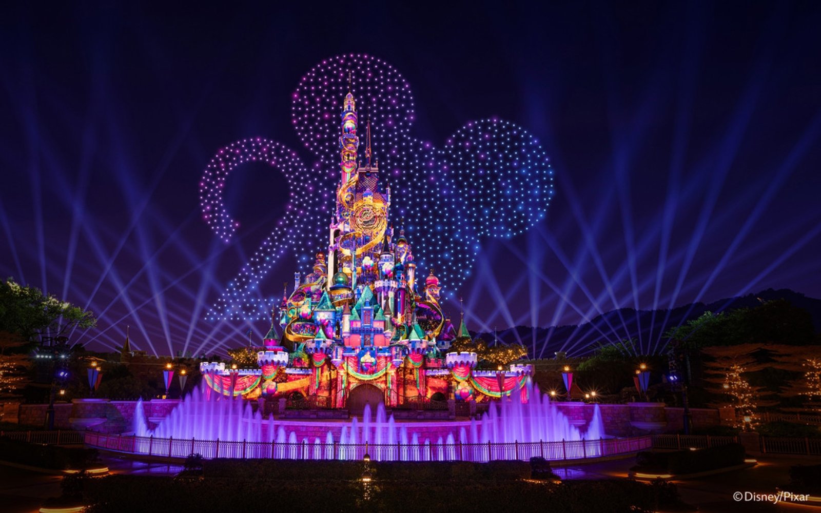 Disneyland Hong Kong castle illuminated with night lights for 20th anniversary celebration.