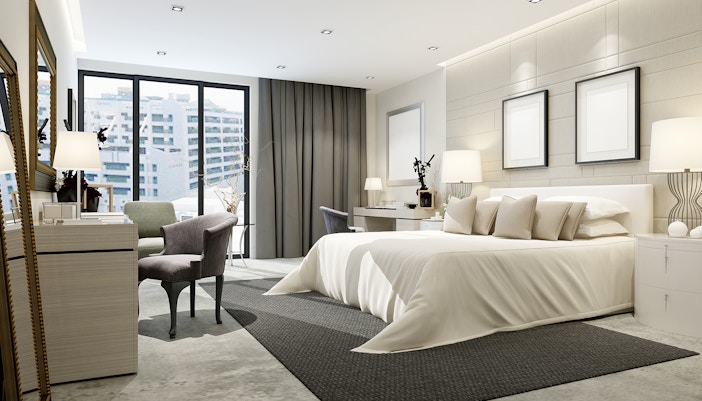 Luxurious hotel room with a king-size bed, modern decor, and city view through large windows.