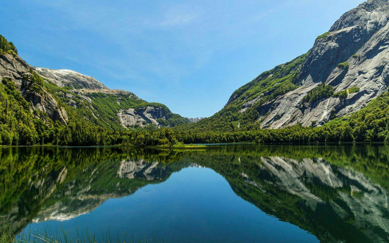 Reflections of Patagonian mountains on calm waters near Puerto Blest, Argentina.