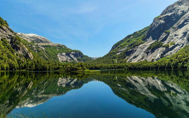 Reflections of Patagonian mountains on calm waters near Puerto Blest, Argentina.