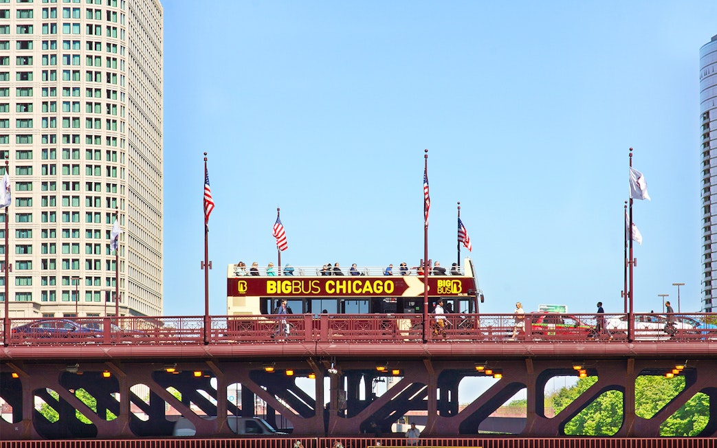 Big Bus Chicago tour crossing a bridge with city buildings in the background.
