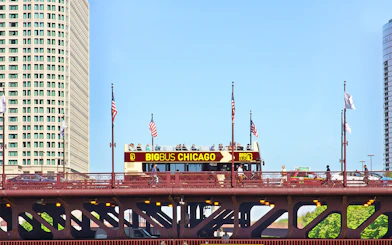 Big Bus Chicago tour crossing a bridge with city buildings in the background.