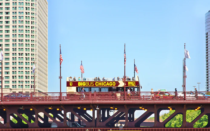 Big Bus Chicago tour crossing a bridge with city buildings in the background.