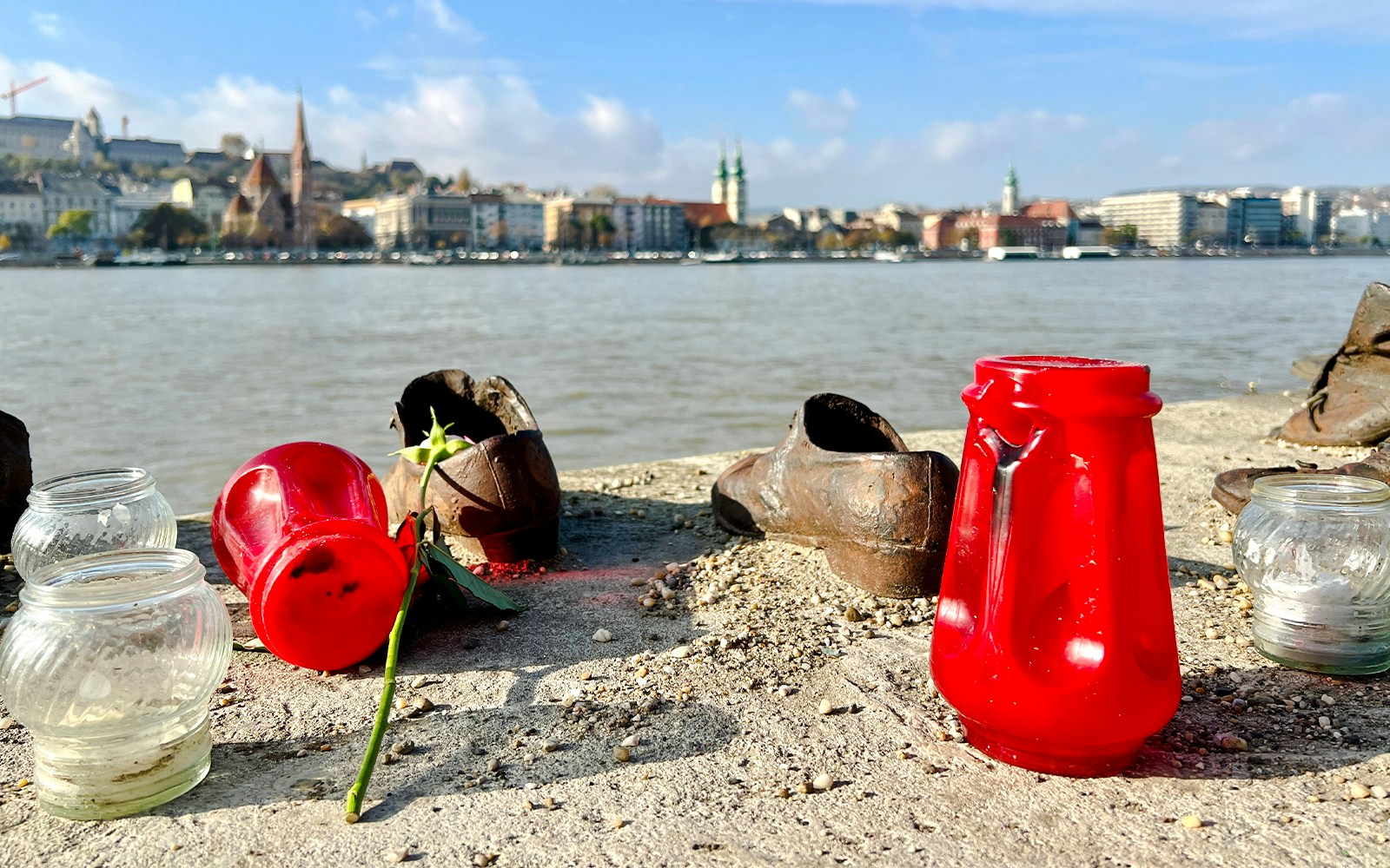 Shoes on the Danube Bank memorial in Budapest with candles and flowers honoring Holocaust victims.