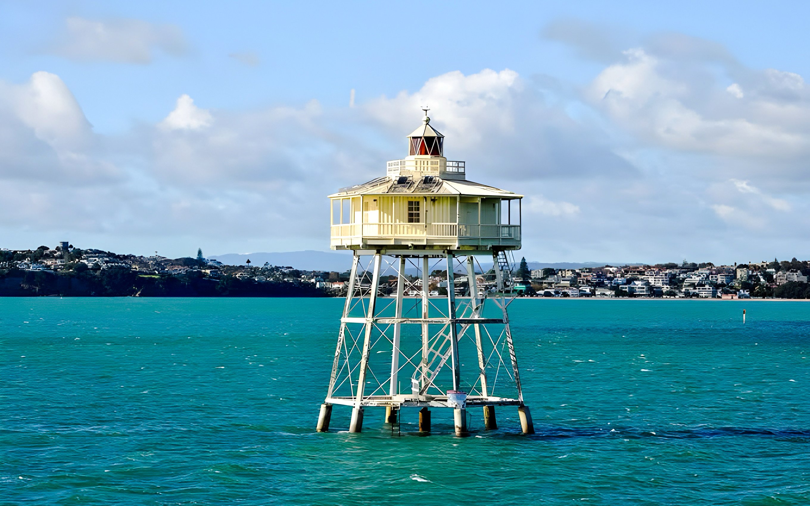 Lighthouse on stilts in a harbor with cityscape in the background, Scenic Wine and Cheese Harbour Cruise.