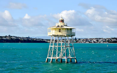Lighthouse on stilts in a harbor with cityscape in the background, Scenic Wine and Cheese Harbour Cruise.