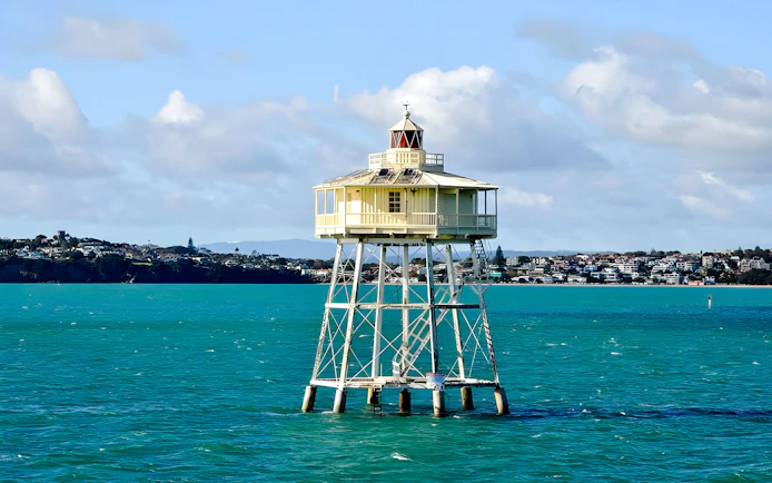 Lighthouse on stilts in a harbor with cityscape in the background, Scenic Wine and Cheese Harbour Cruise.