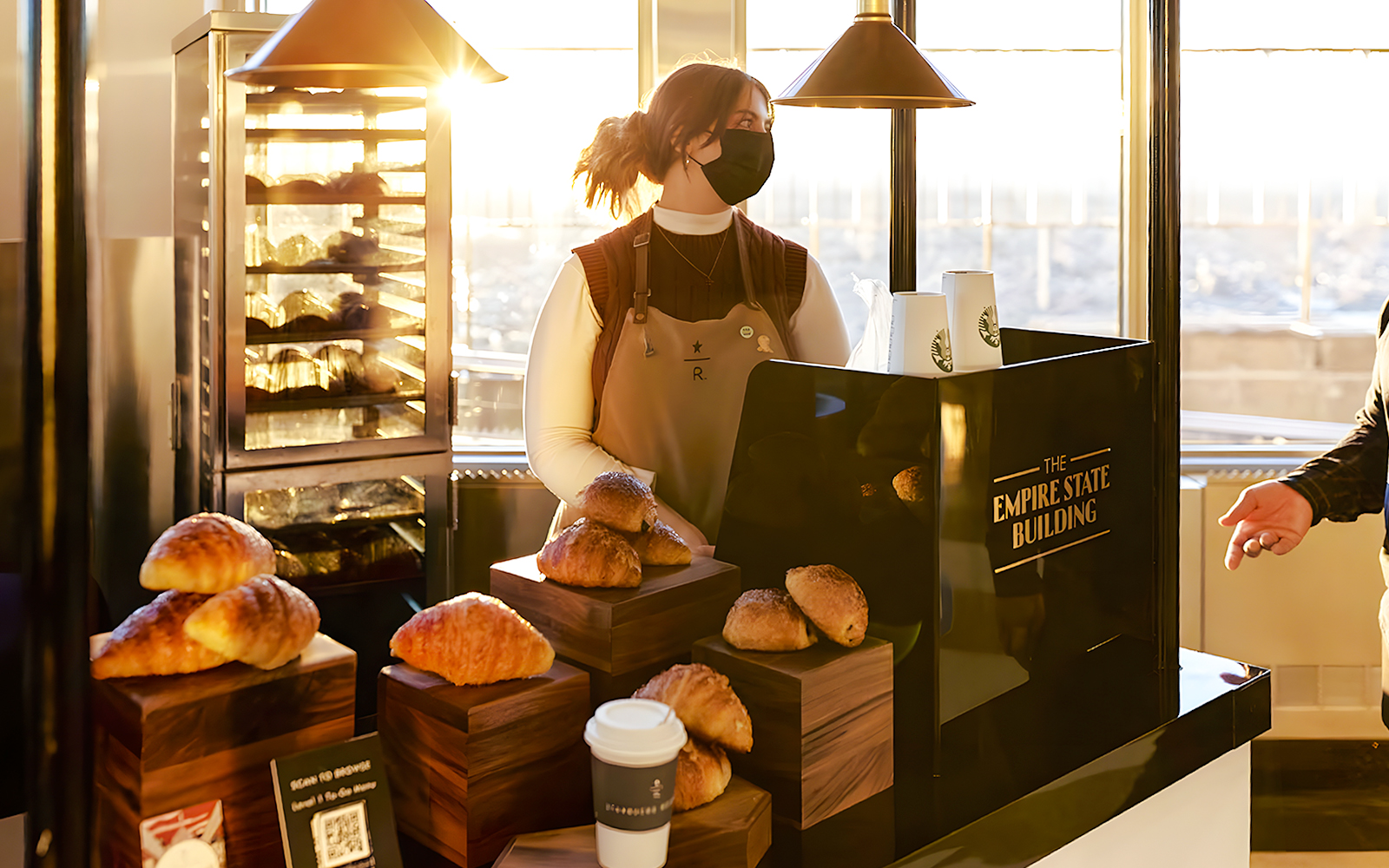 Server at Empire State Building cafe with pastries and coffee.