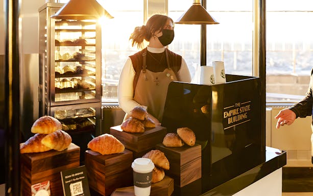Server at Empire State Building cafe with pastries and coffee.