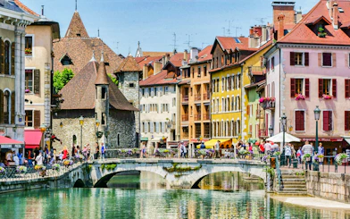 Colorful buildings and a stone bridge over a canal in Annecy, France.