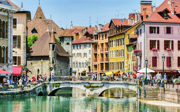 Colorful buildings and a stone bridge over a canal in Annecy, France.