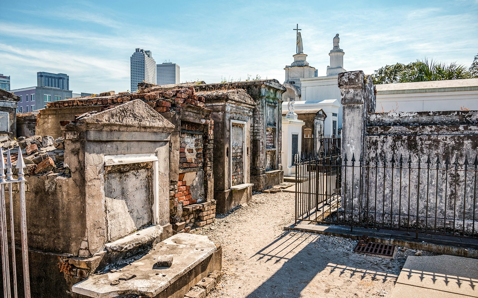 Historic crypts in a New Orleans graveyard with city skyline in the background.