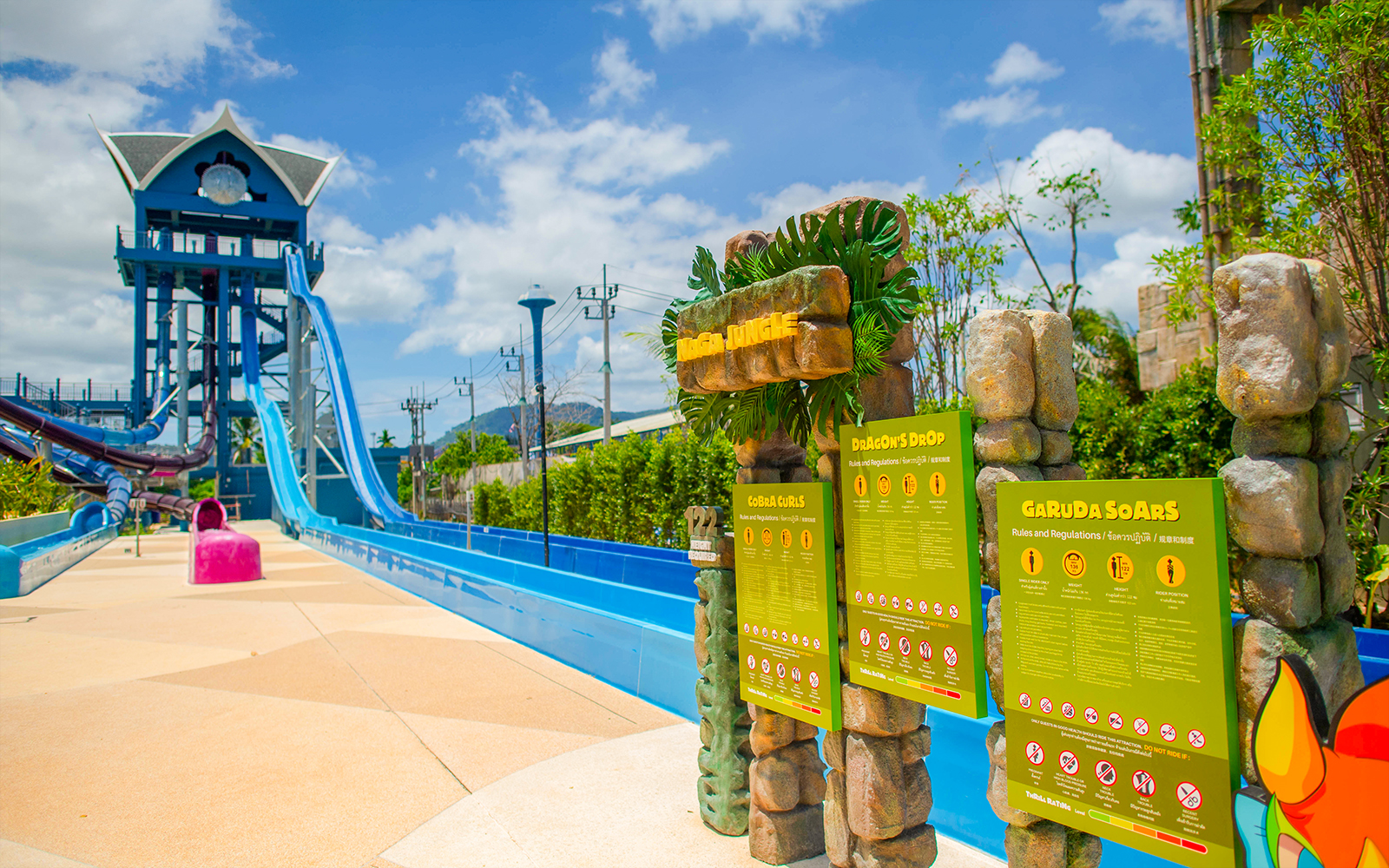 Water slide at Dragon's Drop, Andamanda Phuket with safety signs and lush surroundings.