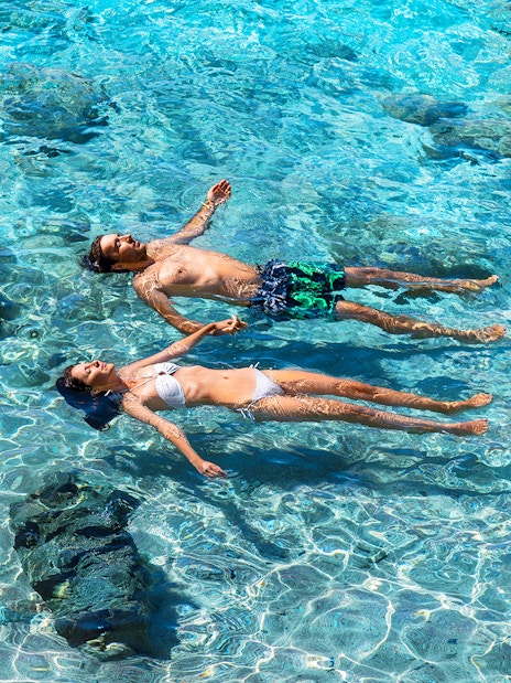 Couple floating in clear waters of La Maddalena Archipelago during motorboat tour.