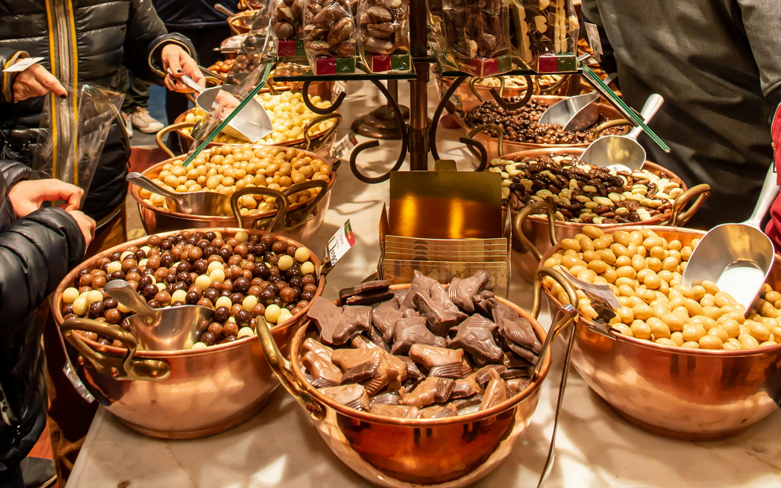 Assorted Belgian chocolates in copper bowls at a Brussels Christmas market.