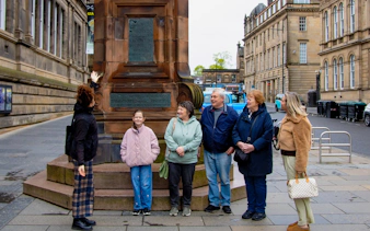 Tour group at a monument during the National Museum of Scotland guided tour in Edinburgh.