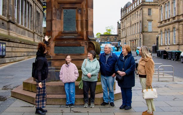 Tour group at a monument during the National Museum of Scotland guided tour in Edinburgh.
