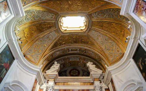 Ornate gold ceiling of a basilica in Rome, featuring intricate carvings and classical art.