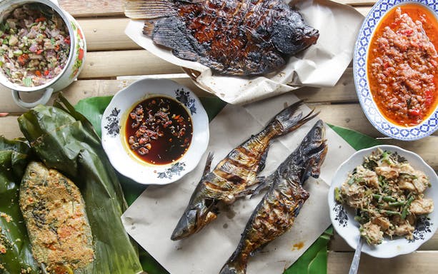 Grilled fish and sambal dishes in traditional Indonesian seafood spread.