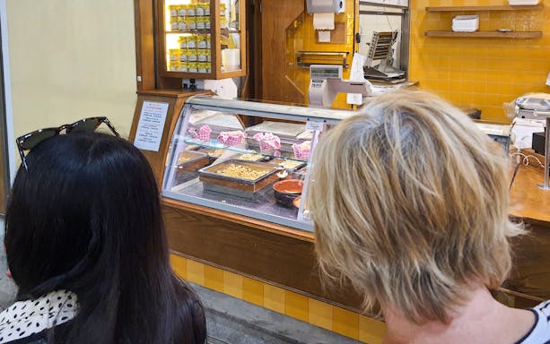Visitors observing a food display at a market during a Florence street food tour.