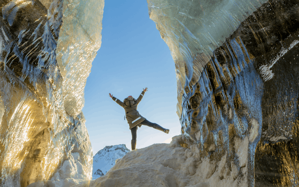 Guests exploring inside Katla Ice Cave with icy walls and snowy landscape.