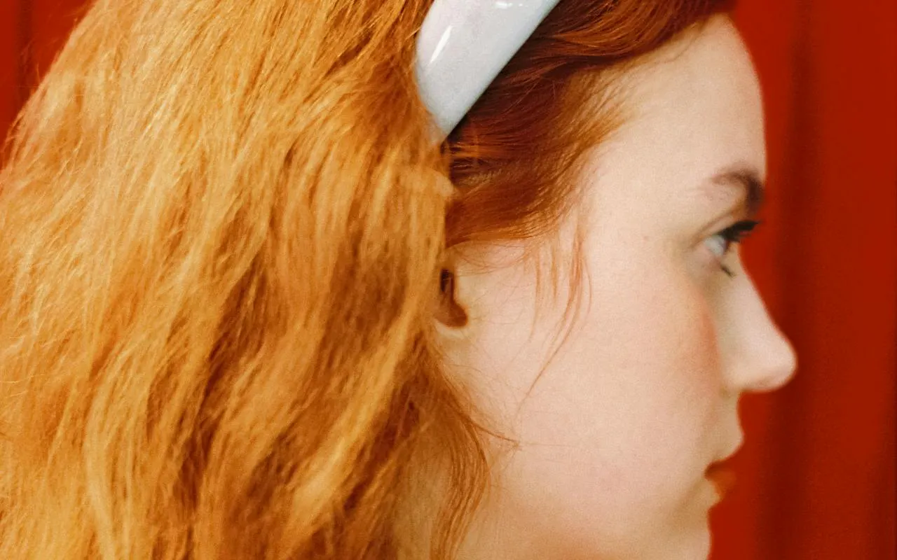 Profile of a person with red hair wearing a headband, related to Barcelona fashion tour.