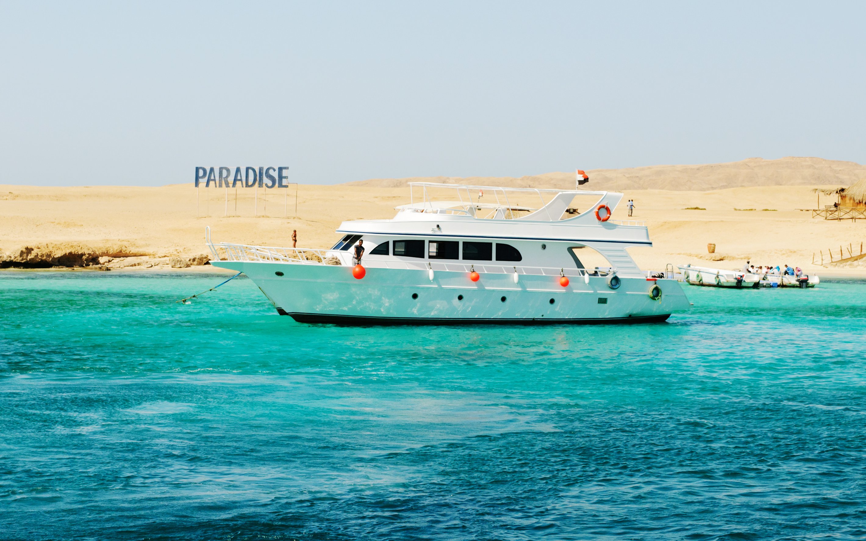 Cruise boat near Giftun Island, Hurghada with "Paradise" sign on sandy shore.