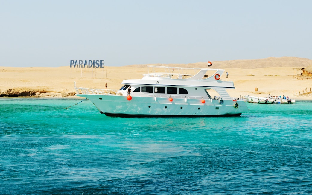 Cruise boat near Giftun Island, Hurghada with "Paradise" sign on sandy shore.