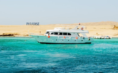 Cruise boat near Giftun Island, Hurghada with "Paradise" sign on sandy shore.