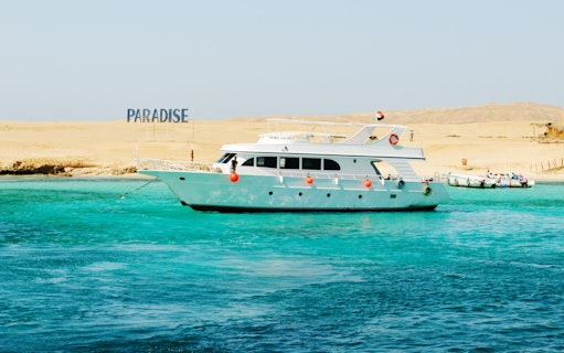 Cruise boat near Giftun Island, Hurghada with "Paradise" sign on sandy shore.