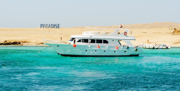 Cruise boat near Giftun Island, Hurghada with "Paradise" sign on sandy shore.