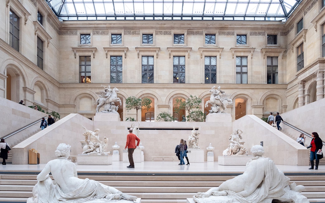 Tourists exploring the Louvre Museum's sculpture gallery in Paris, France.