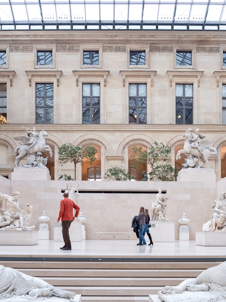 Tourists exploring the Louvre Museum's sculpture gallery in Paris, France.