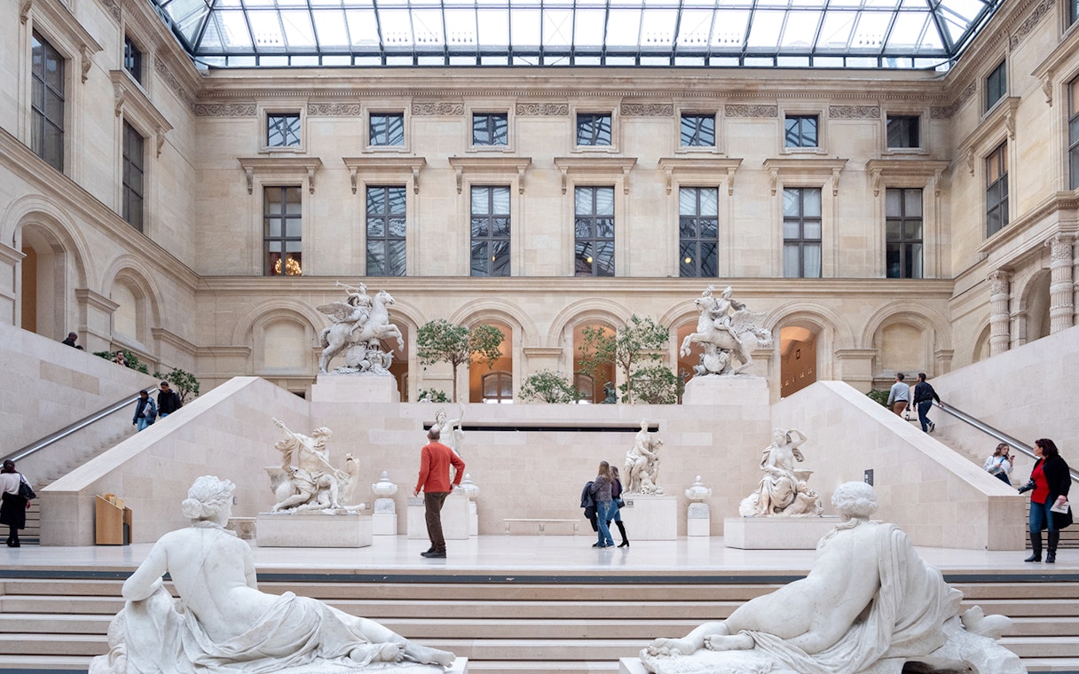 Tourists exploring the Louvre Museum's sculpture gallery in Paris, France.