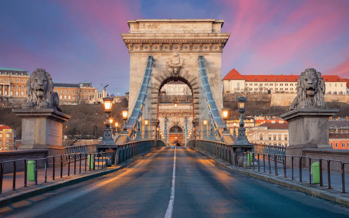 Chain Bridge in Budapest at sunset, view from road with lion statues.