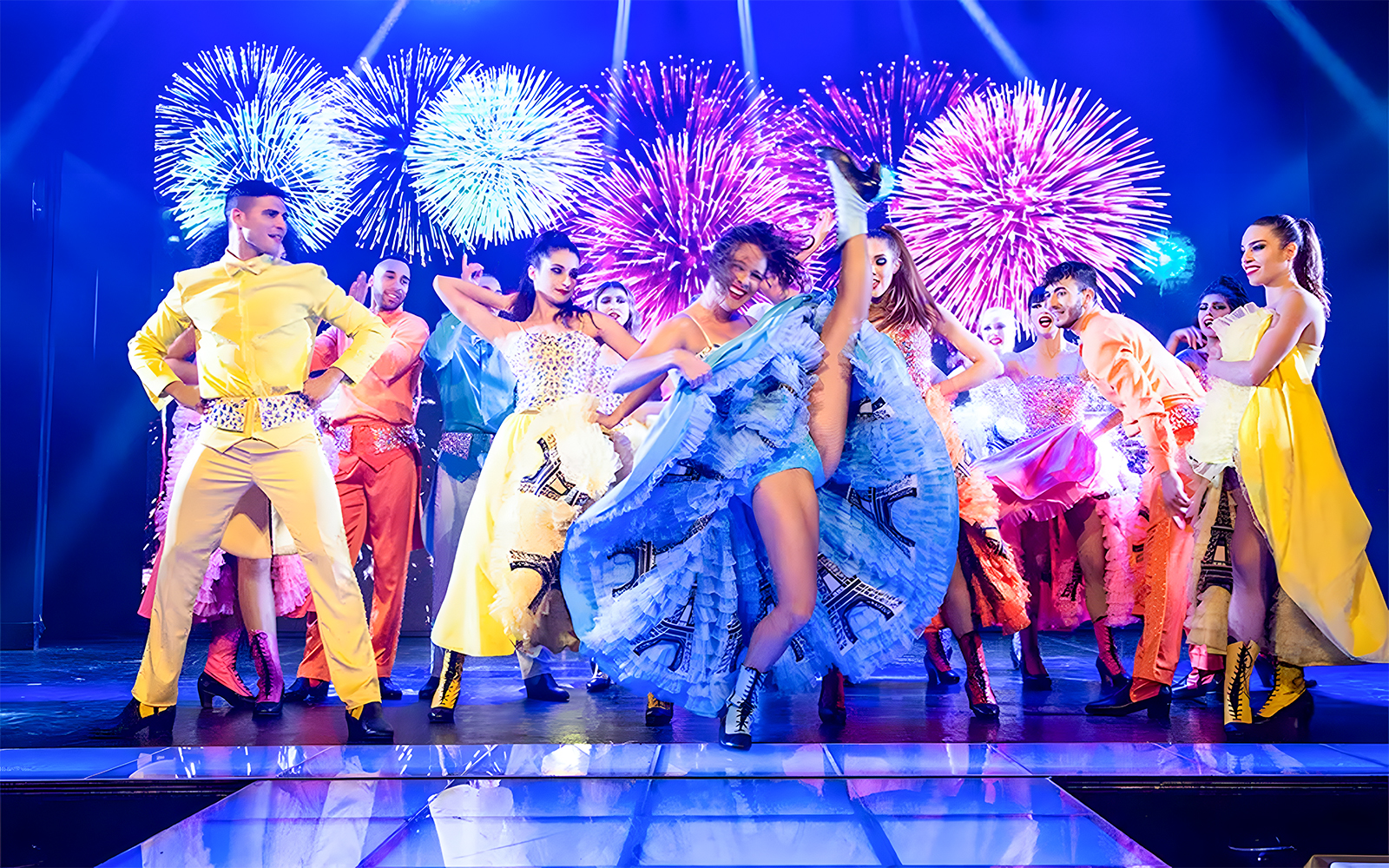 Dancers performing French Cancan at Paradis Latin in Cancun with fireworks in the background.